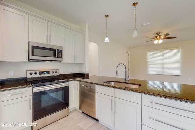 kitchen with stainless steel appliances, white cabinets, pendant lighting, dark stone countertops, and ceiling fan