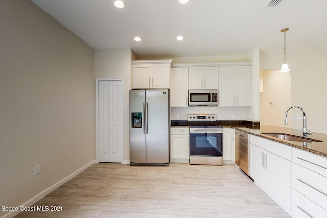 kitchen with stainless steel appliances, sink, pendant lighting, light hardwood / wood-style floors, and white cabinetry