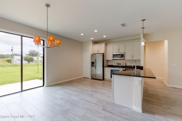 kitchen featuring a wealth of natural light, stainless steel appliances, decorative light fixtures, and white cabinets