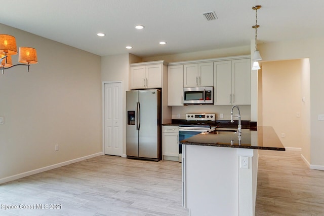 kitchen with appliances with stainless steel finishes, white cabinets, sink, kitchen peninsula, and light wood-type flooring