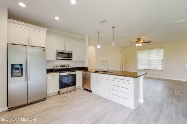 kitchen with appliances with stainless steel finishes, white cabinets, sink, hanging light fixtures, and ceiling fan