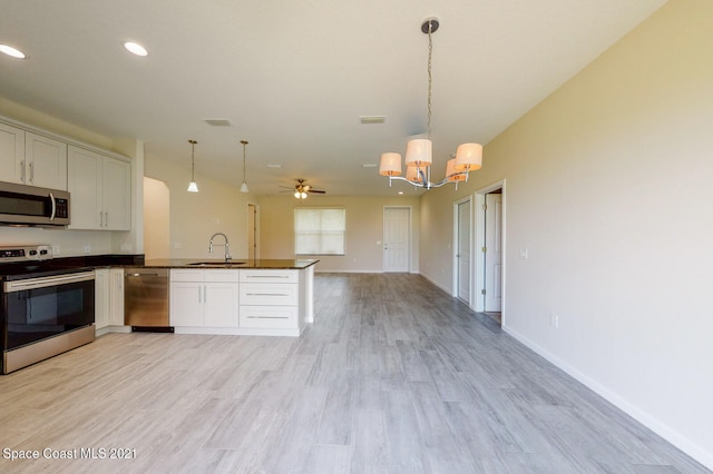 kitchen featuring white cabinets, pendant lighting, light hardwood / wood-style flooring, and appliances with stainless steel finishes