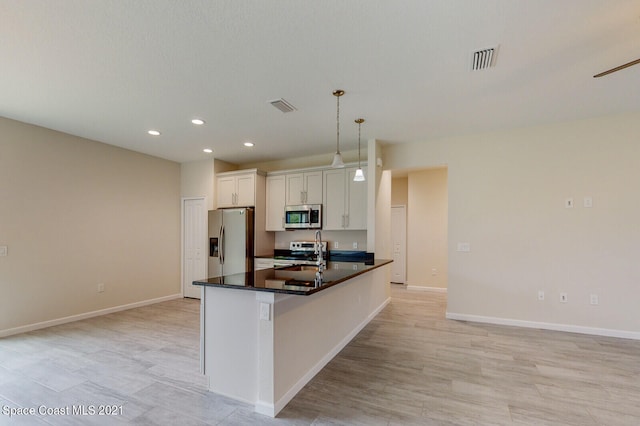 kitchen featuring stainless steel appliances, sink, decorative light fixtures, a kitchen island with sink, and white cabinetry