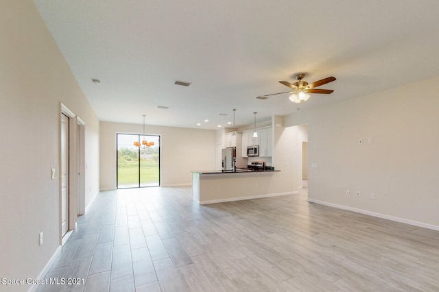 unfurnished living room with ceiling fan with notable chandelier