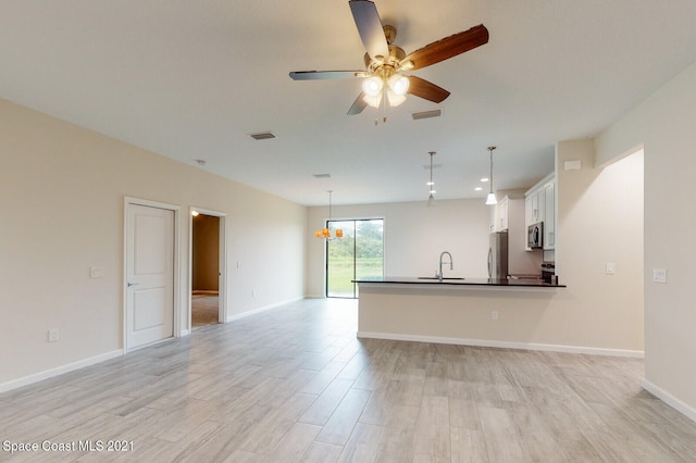 unfurnished living room with ceiling fan with notable chandelier, light hardwood / wood-style flooring, and sink