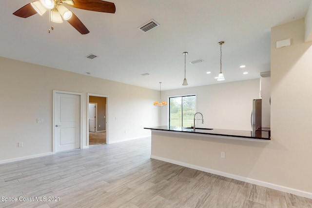 1071 Grapefruit Rd SE, Palm Bay, FL 32909 - kitchen featuring freestanding refrigerator, light wood-style flooring, ceiling fan, dark countertops, and pendant lighting