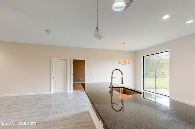 1071 Grapefruit Rd SE, Palm Bay, FL 32909 - kitchen featuring hanging light fixtures, dark stone countertops, light wood-style floors, recessed lighting, and a chandelier