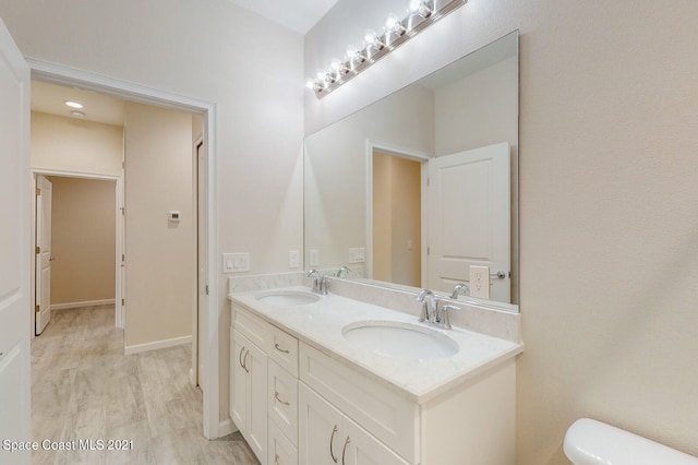 bathroom with hardwood / wood-style flooring, double sink vanity, and toilet