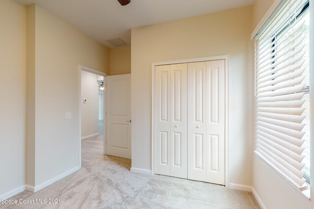 unfurnished bedroom featuring light carpet, a closet, and ceiling fan