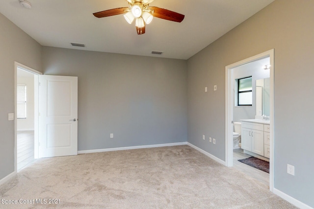 unfurnished bedroom featuring light carpet, sink, ensuite bath, and ceiling fan