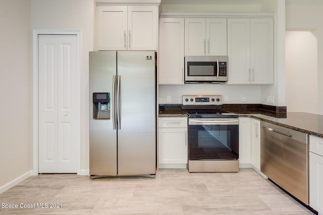 kitchen featuring dark stone countertops, white cabinets, and stainless steel appliances