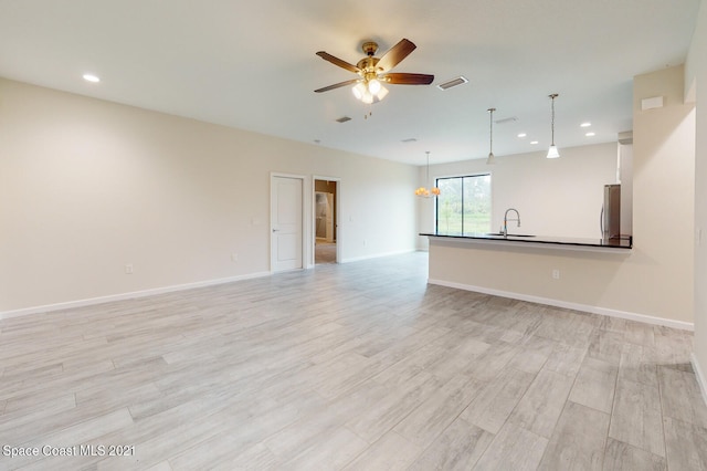 unfurnished living room featuring light hardwood / wood-style flooring, sink, and ceiling fan