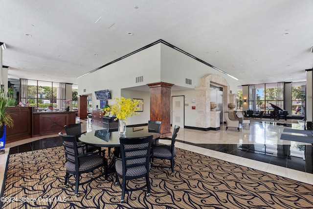 tiled dining area with expansive windows, a textured ceiling, decorative columns, and plenty of natural light