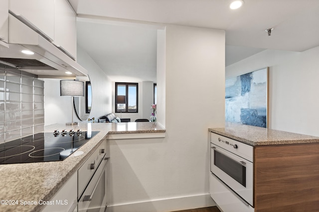 kitchen with oven, decorative backsplash, black electric stovetop, white cabinets, and exhaust hood