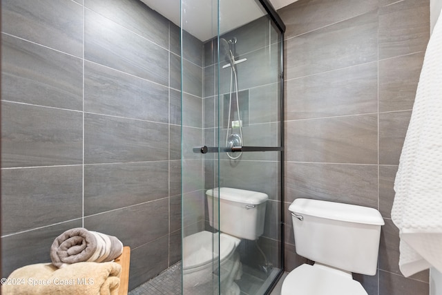 bathroom featuring toilet, tile walls, and a shower with shower door