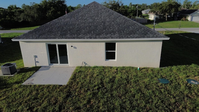 rear view of property featuring a lawn and central AC unit