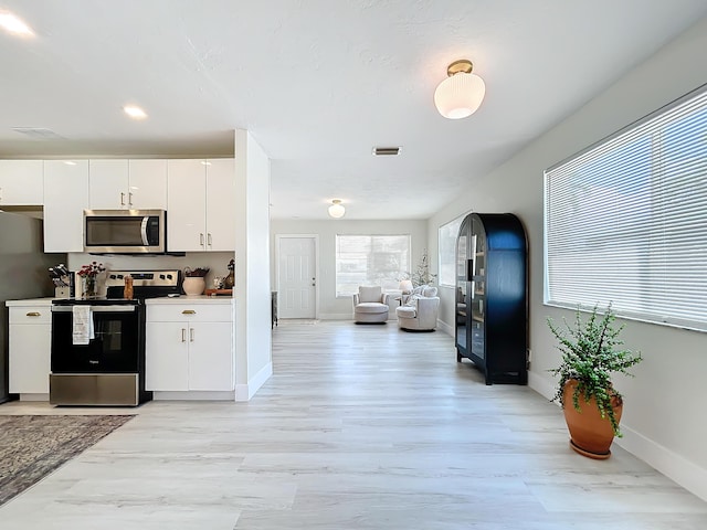 kitchen with white cabinets, stainless steel appliances, and light hardwood / wood-style flooring