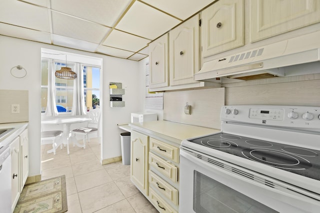 kitchen with a drop ceiling, light tile patterned flooring, and white appliances