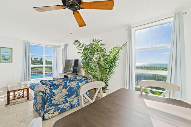 tiled dining room with a wealth of natural light, ceiling fan, and a textured ceiling