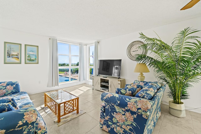 living room featuring ceiling fan, light tile patterned floors, and a textured ceiling