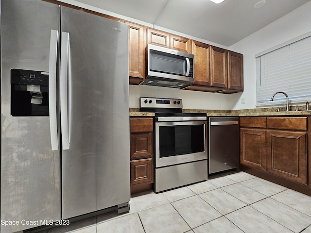 kitchen featuring light stone countertops, appliances with stainless steel finishes, sink, and light tile patterned floors