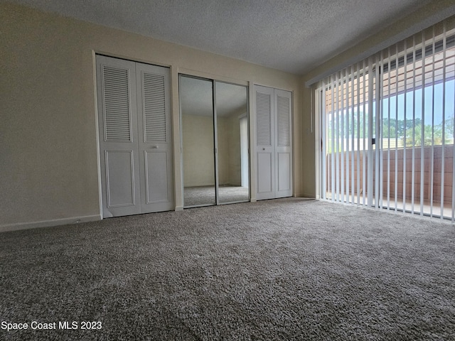 unfurnished bedroom with multiple closets, carpet flooring, and a textured ceiling