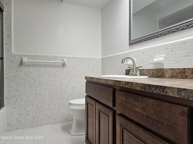 bathroom featuring tile walls, vanity, tile patterned flooring, and toilet