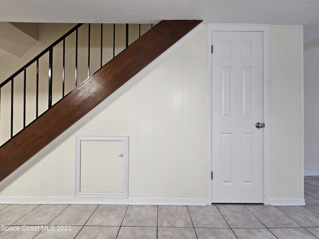 staircase featuring tile patterned flooring and a textured ceiling