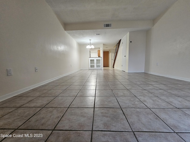 empty room with a notable chandelier and a textured ceiling