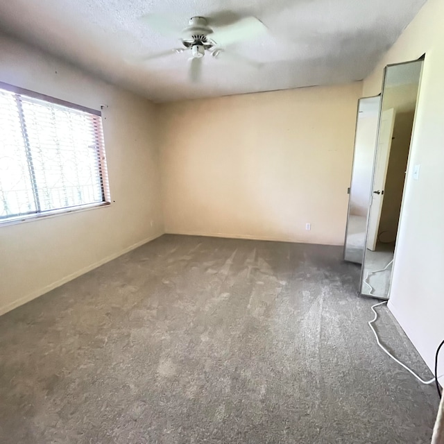 carpeted empty room featuring a textured ceiling and ceiling fan