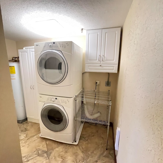 washroom featuring water heater, stacked washer / dryer, a textured ceiling, and cabinets