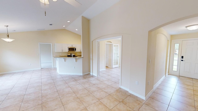 interior space with ceiling fan, light tile patterned floors, and vaulted ceiling