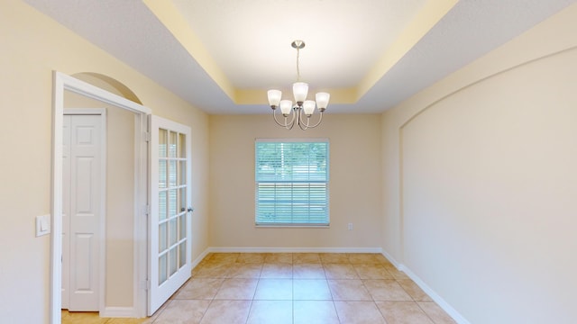 interior space with light tile patterned floors, a tray ceiling, and an inviting chandelier