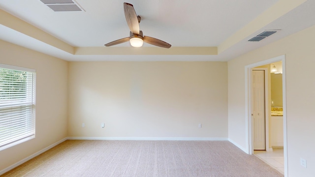 carpeted spare room featuring ceiling fan and a raised ceiling