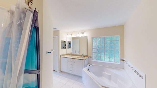 bathroom featuring a textured ceiling, vanity, a relaxing tiled tub, and tile patterned floors