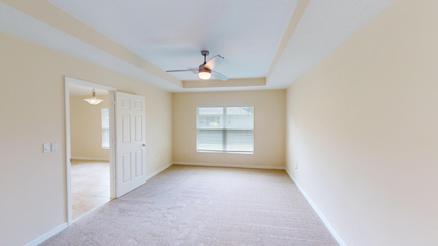 unfurnished room with light carpet, a raised ceiling, and ceiling fan