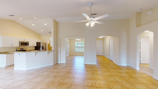 kitchen featuring light stone counters, ceiling fan with notable chandelier, stainless steel appliances, light tile patterned floors, and white cabinetry