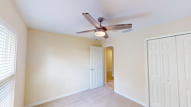 unfurnished bedroom with ceiling fan, a closet, and light carpet