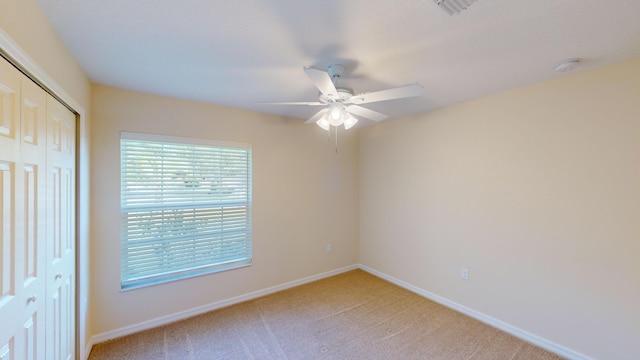 unfurnished bedroom featuring light carpet, a closet, and ceiling fan