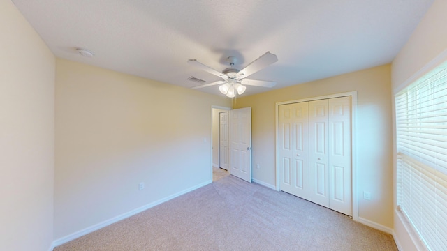 unfurnished bedroom featuring light carpet, a closet, and ceiling fan