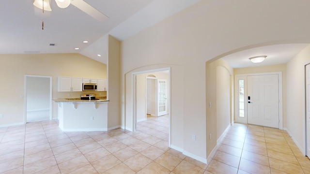 tiled entryway featuring ceiling fan and high vaulted ceiling