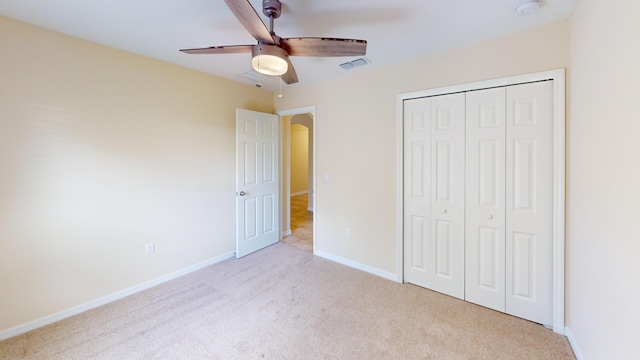 unfurnished bedroom with ceiling fan, light carpet, and a closet