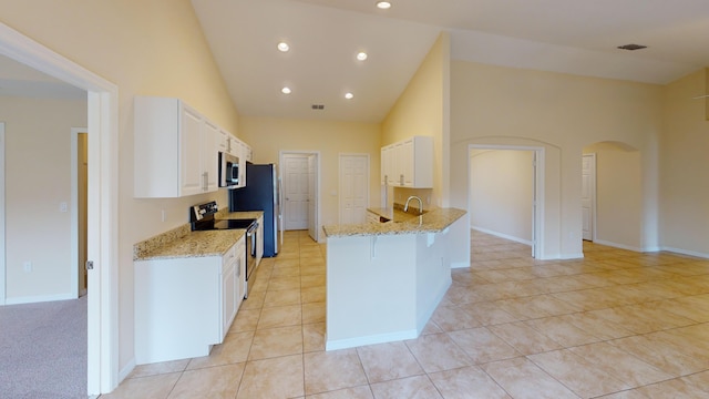 kitchen with a kitchen bar, stainless steel appliances, white cabinetry, and light stone counters