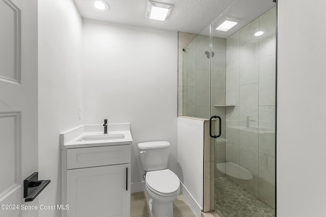 bathroom with a textured ceiling, toilet, a shower with door, and vanity