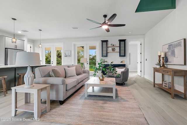 living room with ceiling fan, light hardwood / wood-style floors, and french doors