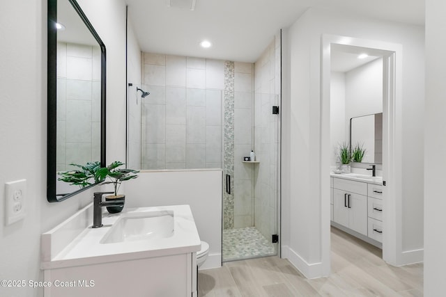 bathroom featuring a shower with shower door, vanity, toilet, and hardwood / wood-style floors