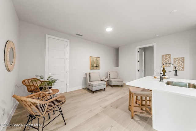 sitting room with light wood-type flooring and sink