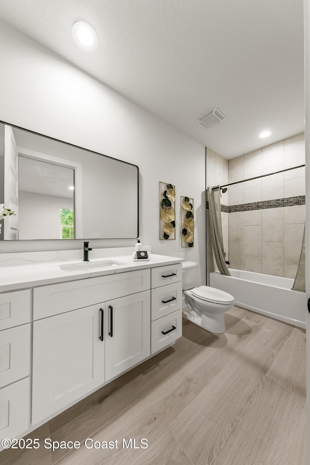 full bathroom with hardwood / wood-style floors, toilet, vanity, and shower / bathtub combination with curtain