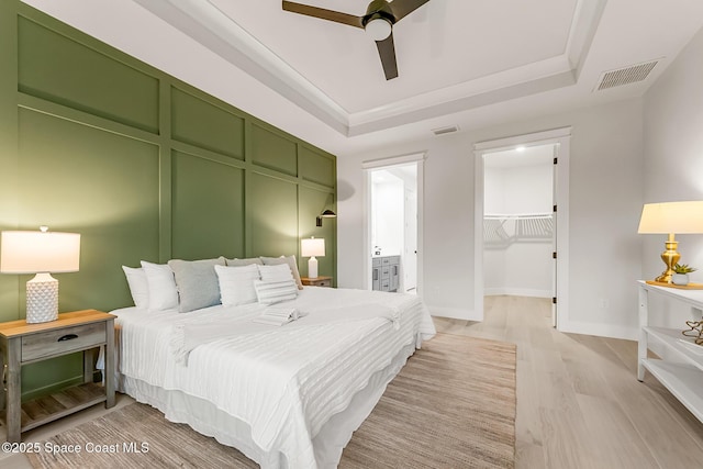 bedroom with a spacious closet, ceiling fan, a closet, and a raised ceiling