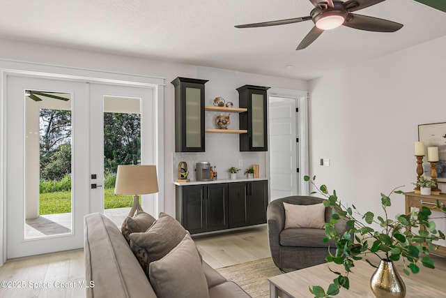 living room featuring light hardwood / wood-style floors, ceiling fan, a wealth of natural light, and french doors